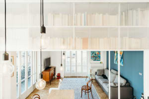 Interior design featuring a minimalist living room with wooden surfaces and furniture, a glass wall, and a blue accent wall.