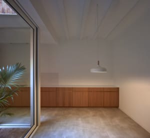 Minimalist residential room with white walls, wooden cabinets, and concrete flooring.