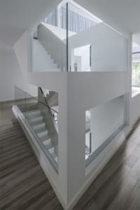 A modern white interior space with glass railings and concrete stairs.