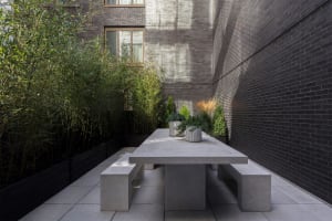 Modern, minimalist outdoor sitting area designed with concrete elements and surrounded by greenery.