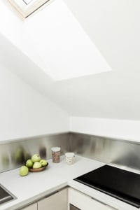 Modern kitchen counter with metallic backsplash and skylight above.