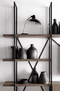 Modern shelves displaying black ceramic vases and a black lamp against a white background.