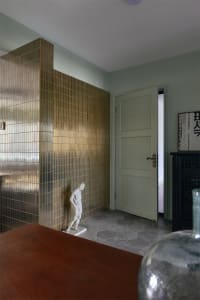 Metal tile wall in an entrance hall, featuring a wooden table and a statue.