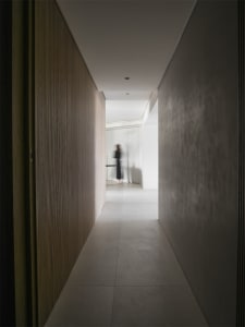 Minimalist corridor with wooden walls and a person walking on the floor.