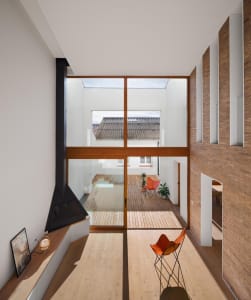 Minimalist living room with wood floors, glass doors, and brick accents.