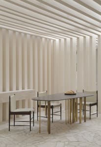 Modern dining room featuring wooden and brass furniture, with a minimalist design aesthetic.