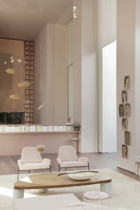 Modern living room with minimalist furniture and warm lighting, featuring soft sofas and a minimalistic table.