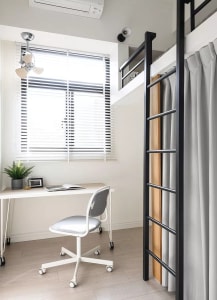 A modern home office with a metal bunk bed and a white desk with a gray chair.