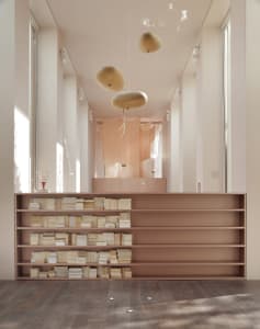 A minimalist library with wooden shelves and soft lighting features.