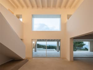 Modern minimalist residential interior with large windows showing a serene outdoor view.