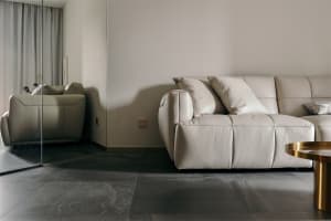 Modern white leather sofa with pillows in a minimalist living room setting.