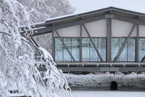 A metallic residential bridge with glass panels over a snowy landscape.