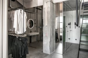 Modern minimalist clothing storage area with concrete walls, glass doors, and metal railings.