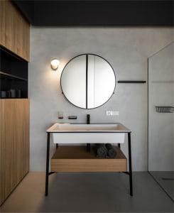 Modern minimalist bathroom featuring a white sink with a black faucet, wooden shelves, and a round mirror.