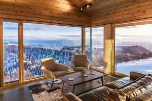 Modern interior design living room with wooden walls, floor-to-ceiling windows showcasing a snowy mountain view, comfortable 