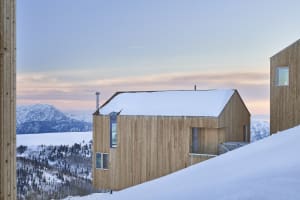 Modern residential house covered in snow with wooden exterior during winter