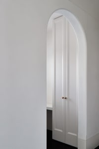 A modern white doorway interior with curved archway and minimalist design.