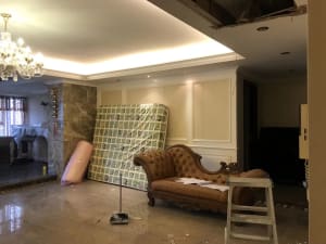 Living room with concrete flooring, marble columns, and renovation tools.