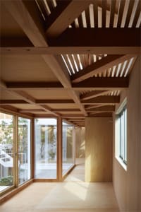 Modern residential interior with wooden floors and beams, featuring a well-lit space with large windows.