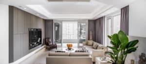 A modern living room featuring neutral-toned upholstery, large windows, and a sleek design aesthetic.