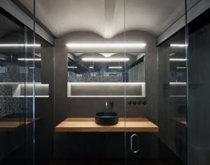 A modern bathroom featuring concrete and glass materials and a sleek black sink.