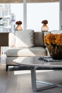 A modern living room with a concrete floor, white furniture, and a coffee table with a vase of flowers.