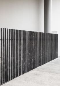 A modern minimalist wall composed of parallel metal rods.