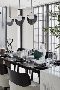 A modern dining room featuring black steel and marble materials.