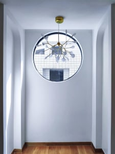 A modern lighting fixture with metal arms and white glass shades hanging from the ceiling.