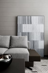 Modern grey sofa in a contemporary living room with abstract wall art and a geometric rug.