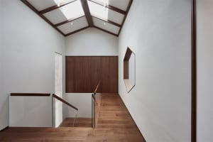 Modern interior design featuring a wooden stairwell with a glass railing and a skylight ceiling.