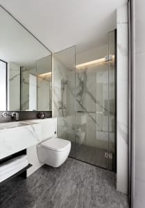 Modern minimalist bathroom with marble finishes and glass shower enclosure.