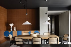 Modern dining room featuring a wooden table with cane chairs and pendant lighting.