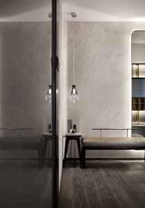Modern home entry with concrete walls, a metal and leather bench, and minimalist lighting fixture.
