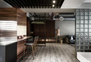 A modern living room with metallic decor, including a sleek bar counter and chairs, a cozy seating area with a sofa, and a st