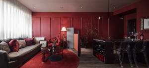 A modern residential interior featuring a living room with a red accent wall, marble coffee table, glass side table, and meta