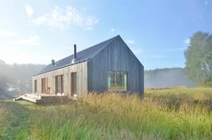 A minimalist residential exterior with a wooden exterior and large glass windows and doors.