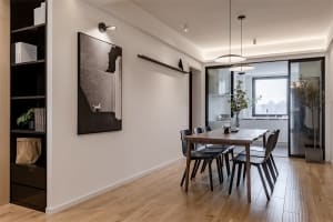 Modern dining room featuring a wooden table with black chairs and decorative elements.