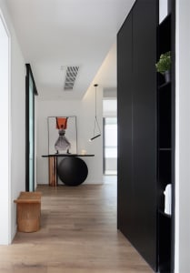A modern interior design corridor with wooden flooring, a black table, and a black lamp hanging from the ceiling.