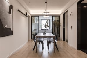 A minimalist dining room with a wooden table and black chairs, featuring modern decor and a sleek design.