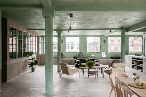 A modern industrial living room with a concrete ceiling, wooden furniture, and glass windows.