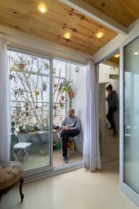 A modern living room with glass walls, wooden finishes, and textile elements.