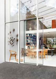 Modern interior living room with floor-to-ceiling glass walls and a library area.