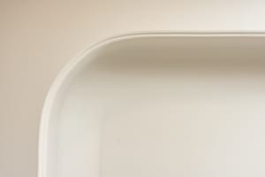 Close-up image of a ceramic bathtub with a curved edge and smooth surface.