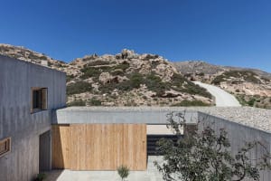 A modern building with concrete exterior and minimalist design, featuring a rocky hill in the background.