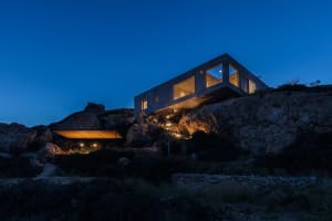 A modern house with a concrete exterior illuminated at night.