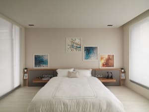 Modern minimalist bedroom with a white bed, white bedding, and abstract paintings on the wall.