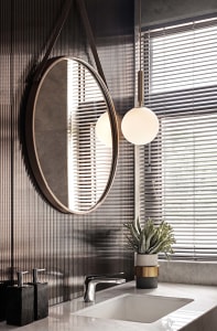 Modern bathroom with metal-textured wall and circular mirror above sink.