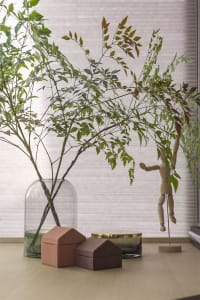 A modern decorative planter with green leaves and house-shaped boxes on a wooden surface.