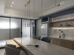 Modern kitchen with marble countertops, wooden cabinets, and glass shelves.